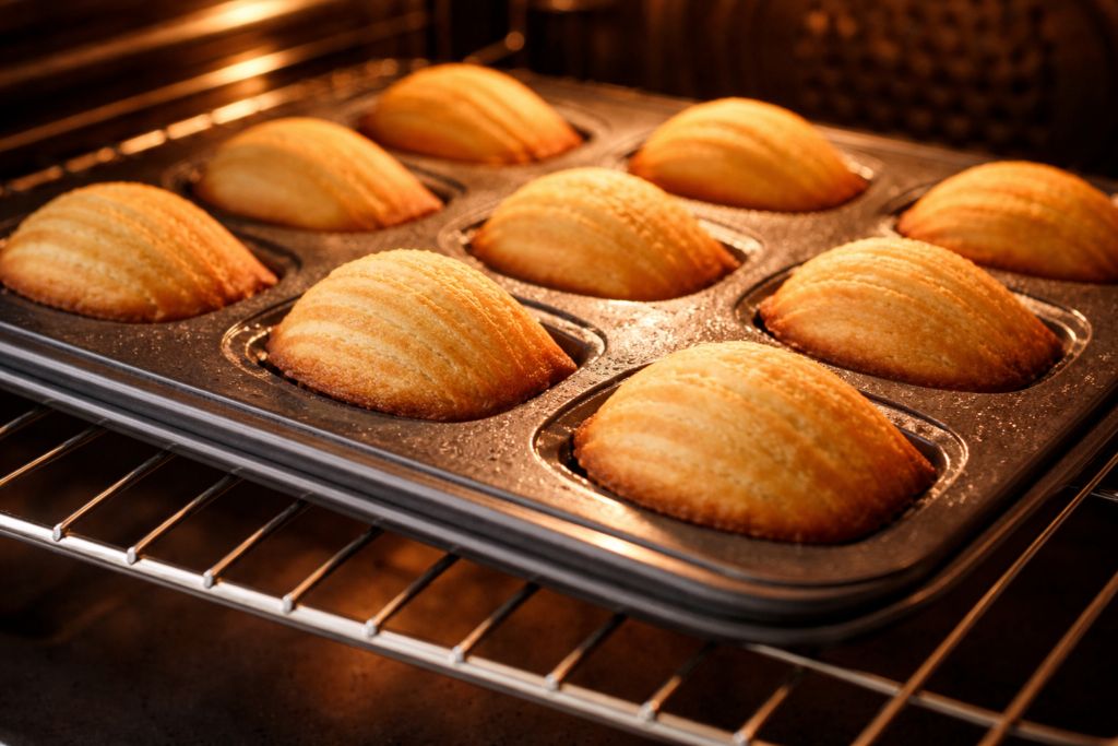 Les Madeleines artisanales Dorées de Mamie Jeanne – Notre Produit Phare Photo de madeleines dans leurs moule qui dorent au four